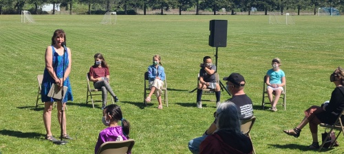 Rachel Kirby, in front of students, speaking at microphone to gathered crowd